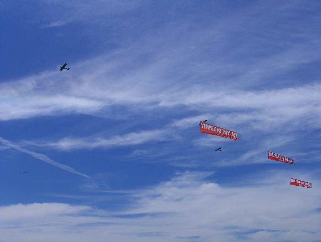 Small planes tow red letter banners across the sky